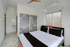 A bedroom with a bed, a wardrobe, an air conditioning unit, and a window with blinds. - Super Hotel O Gandimaisamma Thalli (Hyderabad)