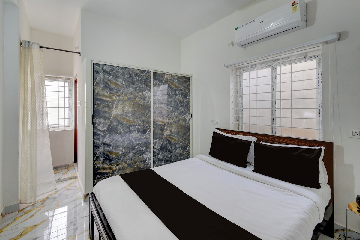A bedroom with a bed, a wardrobe, a window, and an air conditioning unit.
