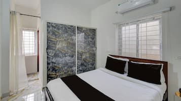 Un dormitorio con cama, armario, ventana y equipo de aire acondicionado.