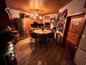 Eine gemütliche Küche mit Holzschränken, einem Esstisch mit Stühlen und einem Kühlschrank.