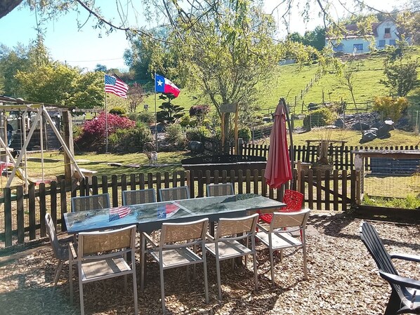 Eine Terrasse im Freien mit Tisch und Stühlen, umgeben von einem Holenzaun, und Flaggen der USA und von Texas.