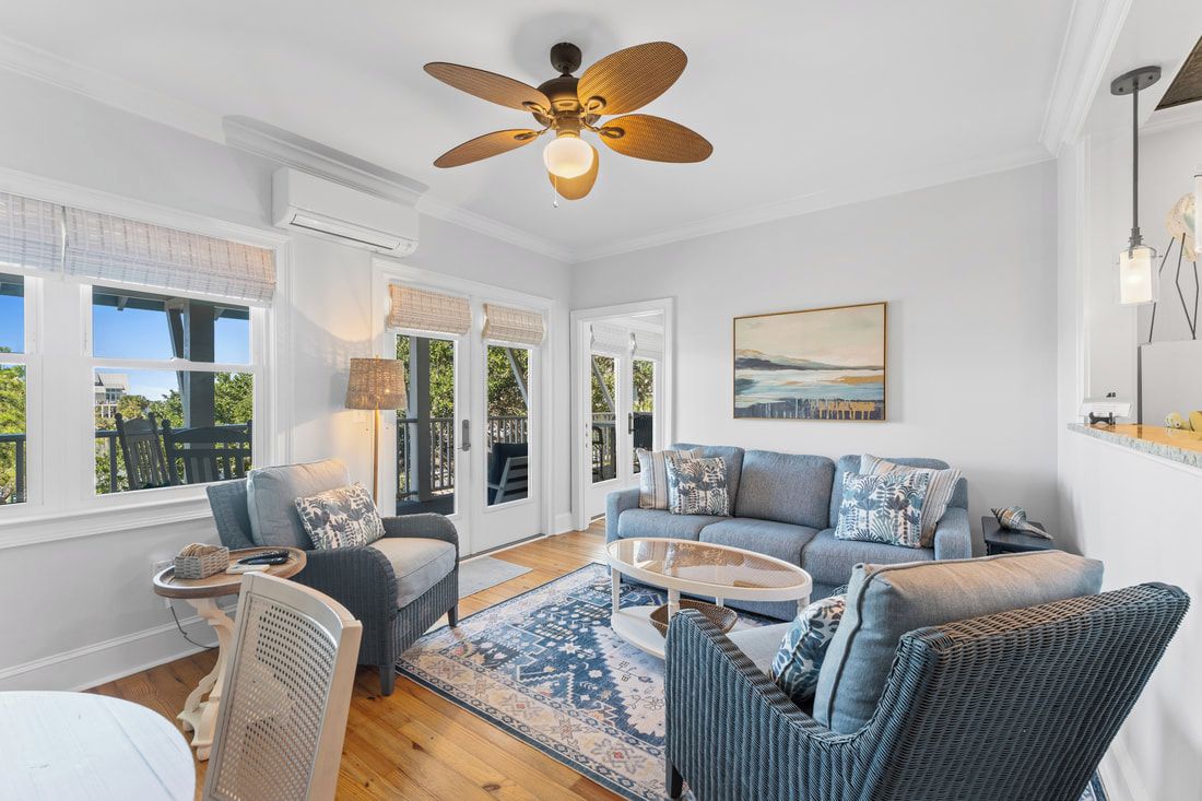 A spacious living room with a ceiling fan, a sofa set, a coffee table, and a patterned rug.