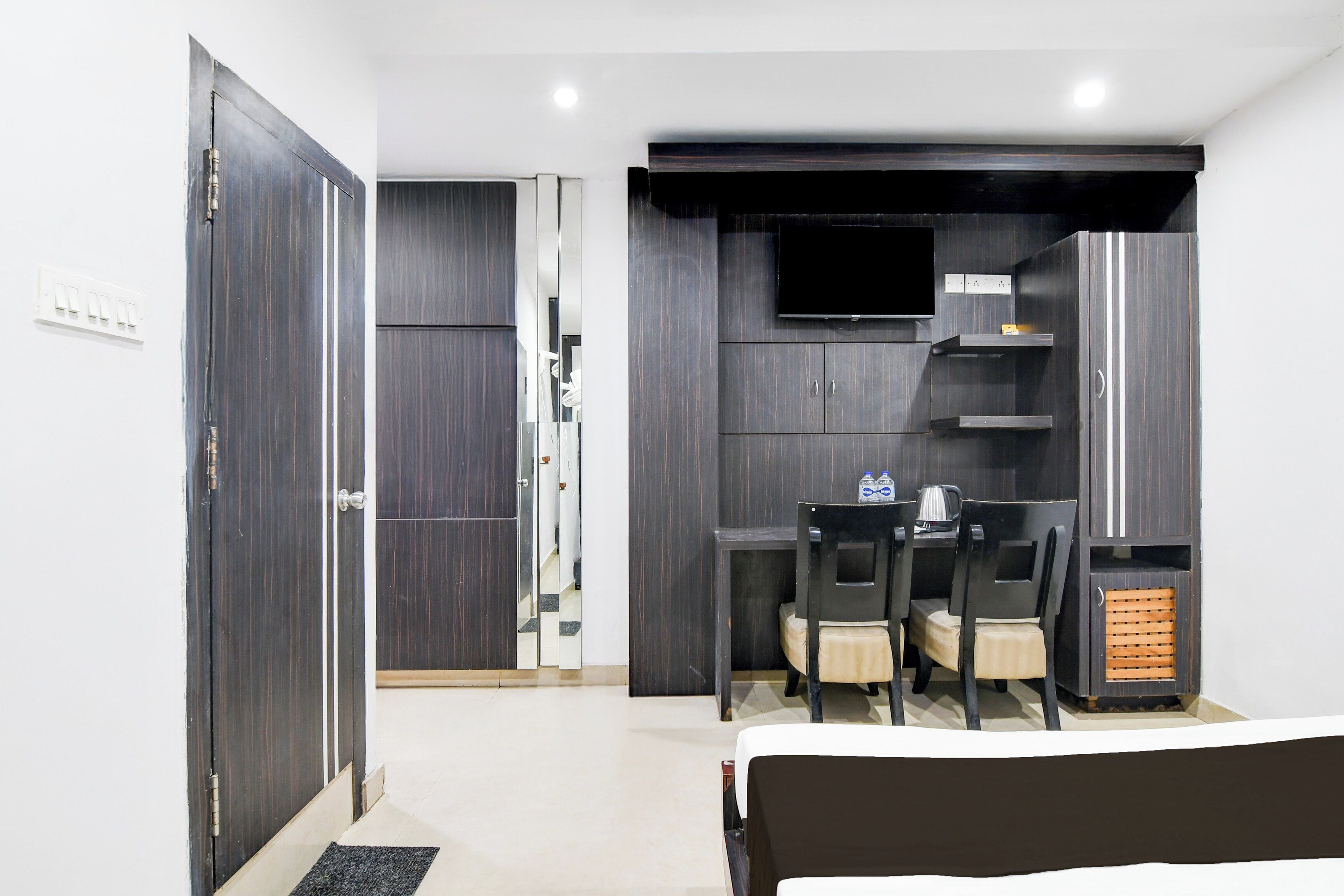 Habitación de hotel con cama, escritorio con silla, televisión y una pequeña zona de kitchenette.
