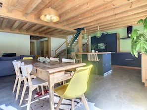 A dining area with a wooden table and chairs, a staircase, and a kitchen area with cabinets and a plant. - Le Vivier (6 People) A peaceful setting with a view of the mountains. Private parking (Saint-Gervais-les-Bains)