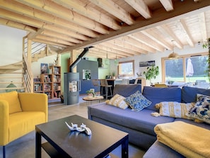 A modern living room with a sofa, a yellow armchair, and a coffee table. There is a staircase leading to an upper level, and a kitchen area is visible in the background. - Le Vivier (6 People) A peaceful setting with a view of the mountains. Private parking (Saint-Gervais-les-Bains)