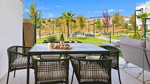 An outdoor patio with a table and chairs, a bottle of wine, and a bowl of olives. - Garden apartment in La Cala Sunset (Mijas Costa)
