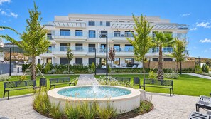 A modern building with multiple balconies, a central fountain, and a well-maintained garden. - Garden apartment in La Cala Sunset (Mijas Costa)