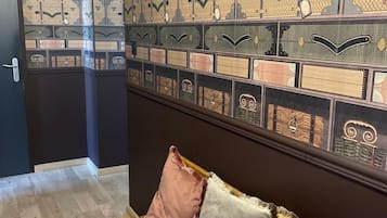 A room with a wooden bench, a wall of patterned storage boxes, and a door leading to another area.