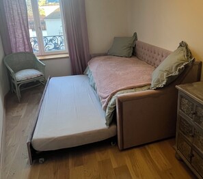 Une petite pièce comprenant un lit, une chaise et une commode.