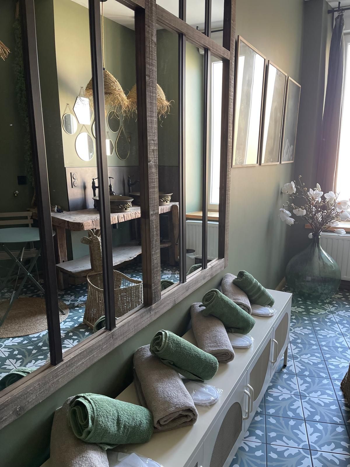 Une salle de bain avec un grand miroir, un lavabo et un porte-serviettes avec des serviettes.