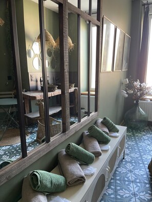 Une salle de bain avec un grand miroir, un lavabo et un porte-serviettes avec des serviettes.