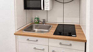 Eine Küche mit Spüle aus Edelstahl, einer Mikrowelle und einer schwarzen Induktionskochplatte.