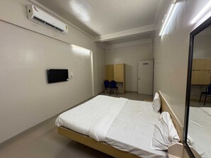 Ein Hotelzimmer mit einem Bett, einem Fernseher, einem Kleiderschrank und einem Spiegel.