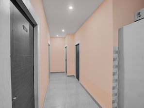 A corridor with doors, a tiled wall, and a ceiling with recessed lighting. - Deluxe Room Hotel Khushi in (Bhubaneshwar)