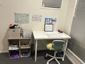 Un espacio de trabajo con un escritorio, una silla y estanterías con libros y material de oficina.