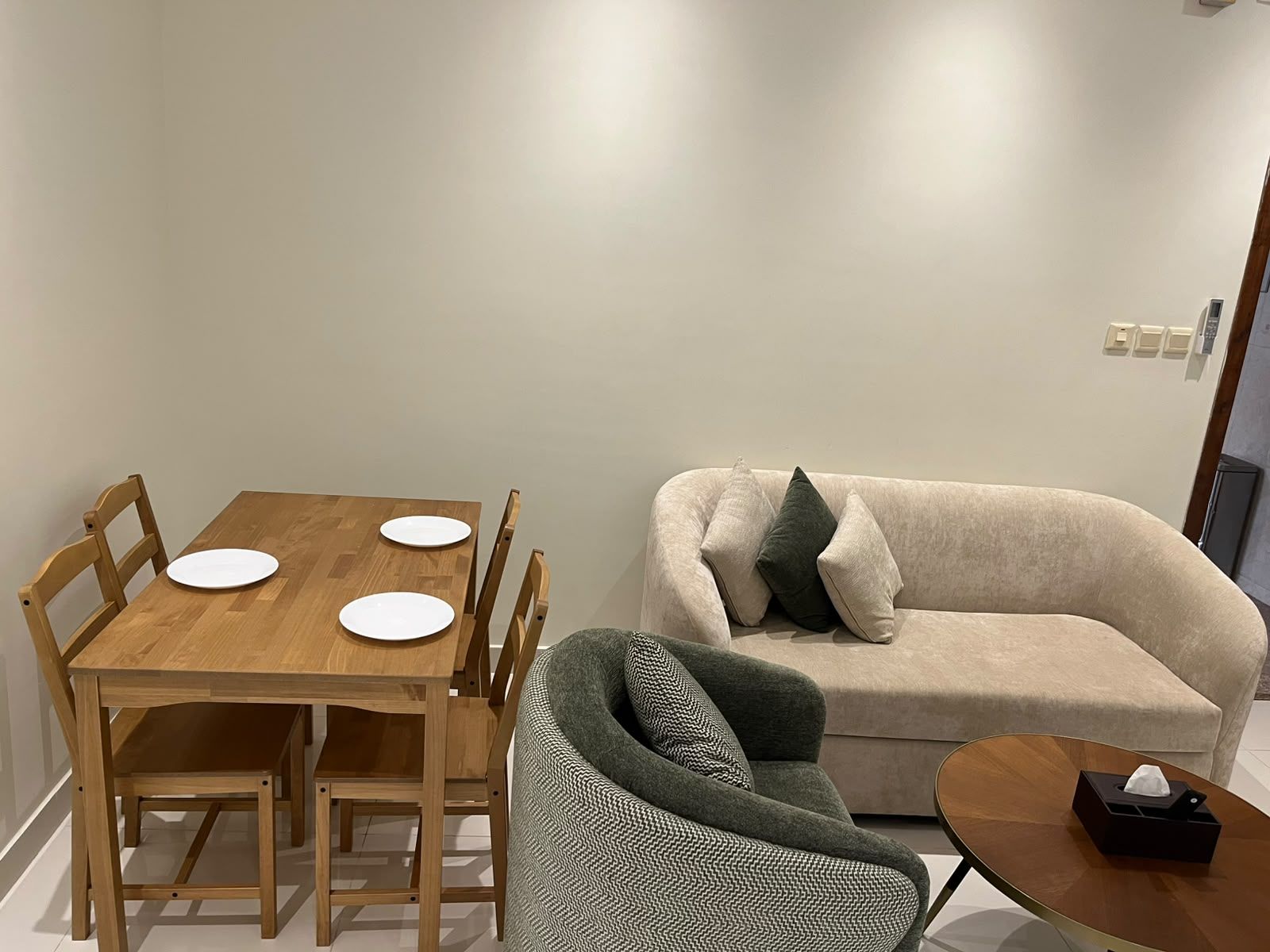 A dining table with four white plates and a wooden chair.