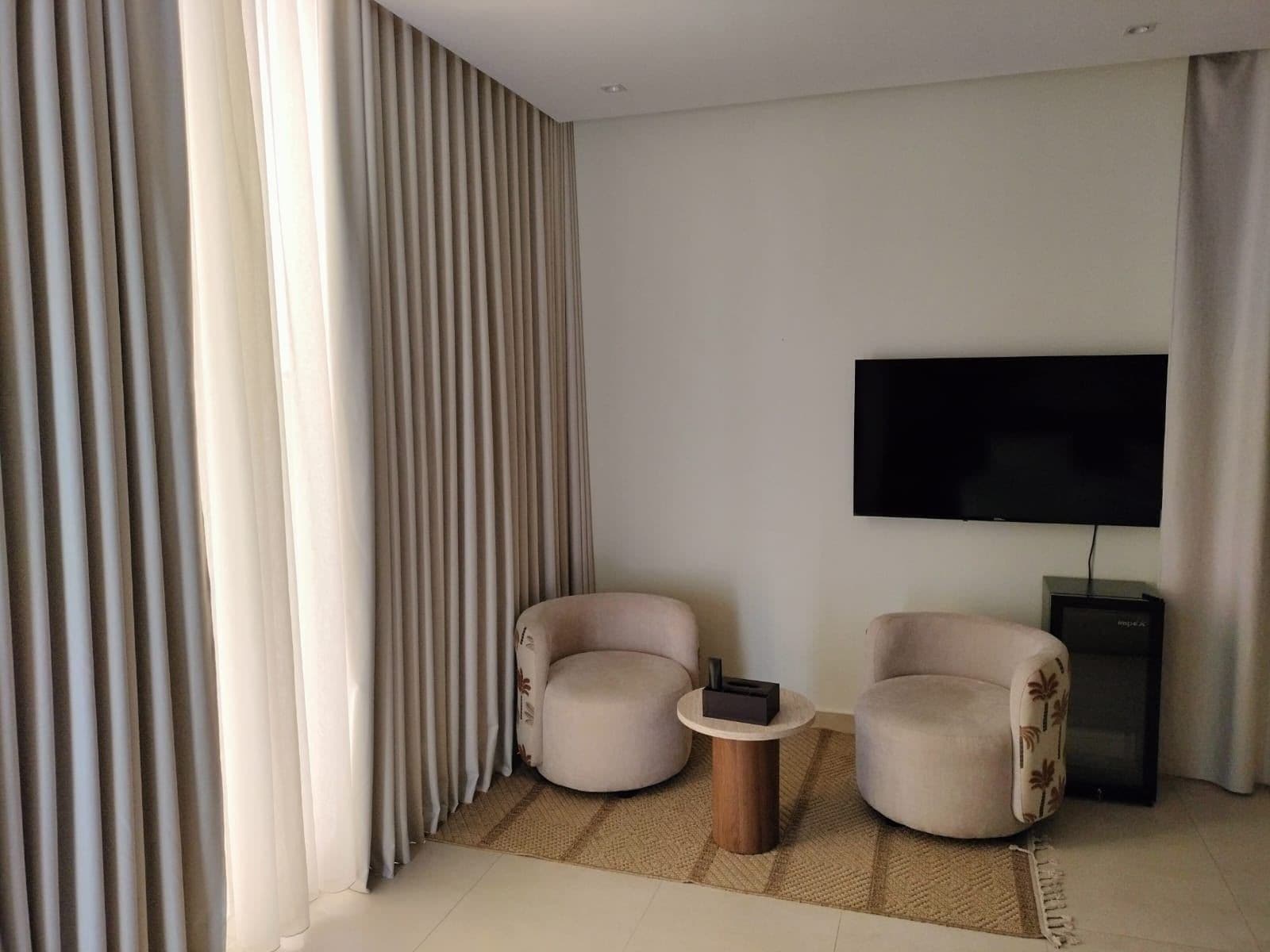 A modern living room with two armchairs, a coffee table, and a flat-screen TV mounted on the wall.