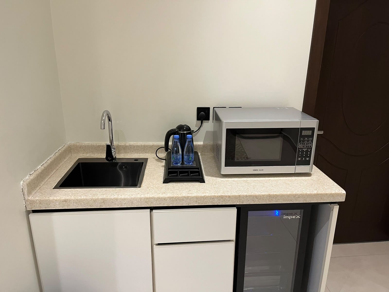 Une petite cuisine équipée comprenant un évier, une bouilloire, un four à micro-ondes et un lave-vaisselle.