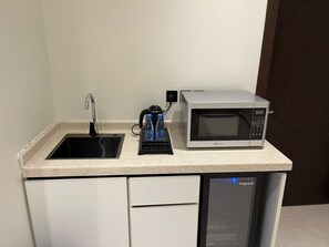 A compact kitchenette with a sink, a kettle, a microwave, and a dishwasher.