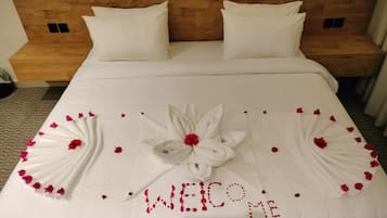 Een keurig opgemaakt bed met een welkomstmatje en rozenblaadjes op het laken.