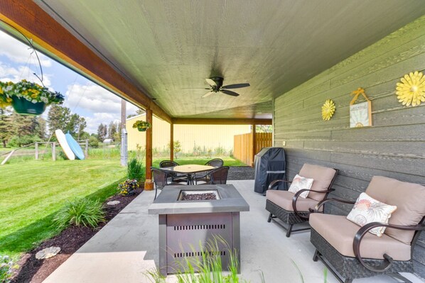 Une terrasse extérieure dotée d’un foyer, de sièges et d’un ventilateur de plafond.