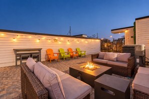 An outdoor patio with wicker furniture, a fire pit, and string lights. - Nashville-themed House 12 South Gulch Sleeps 12 (Nashville)
