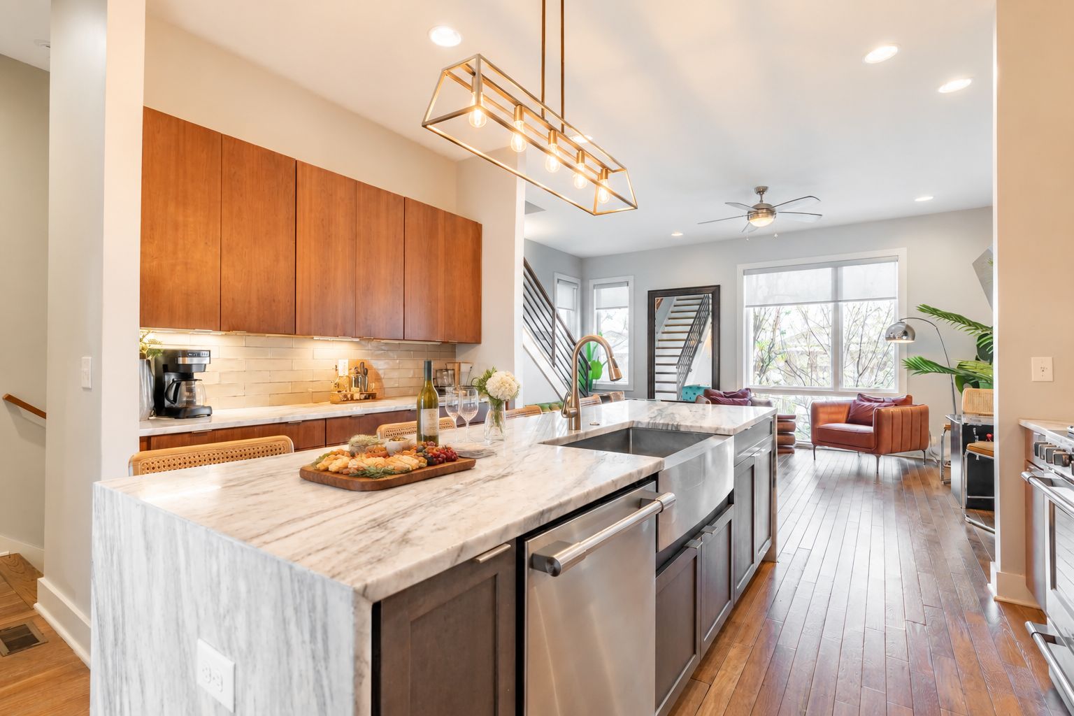 A modern kitchen with a marble island, wooden cabinets, and a built-in dishwasher.