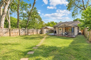 A backyard with a covered patio, a wooden deck, and a fenced area. - East Nashville Craftsman - Sleeps 10 - Media Room (Nashville)