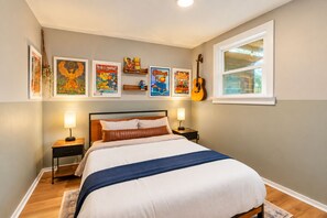 A bedroom with a bed, two bedside tables, a guitar, and artwork on the wall. - East Nashville Craftsman - Sleeps 10 - Media Room (Nashville)
