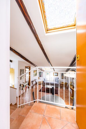 A staircase with a white railing leading to a living area with a sofa and a table. - Alessio's House by Napoliapartments (Naples)