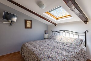 A bedroom with a bed, a TV, a skylight, and a framed picture on the wall. - Alessio's House by Napoliapartments (Naples)