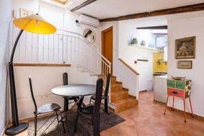 A dining area with a table and chairs, a staircase, a kitchen, and a small cabinet with drawers. - Alessio's House by Napoliapartments (Naples)