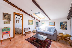 A living room with a sofa, a coffee table, a patterned rug, a small side table, and artwork on the walls. - Alessio's House by Napoliapartments (Naples)