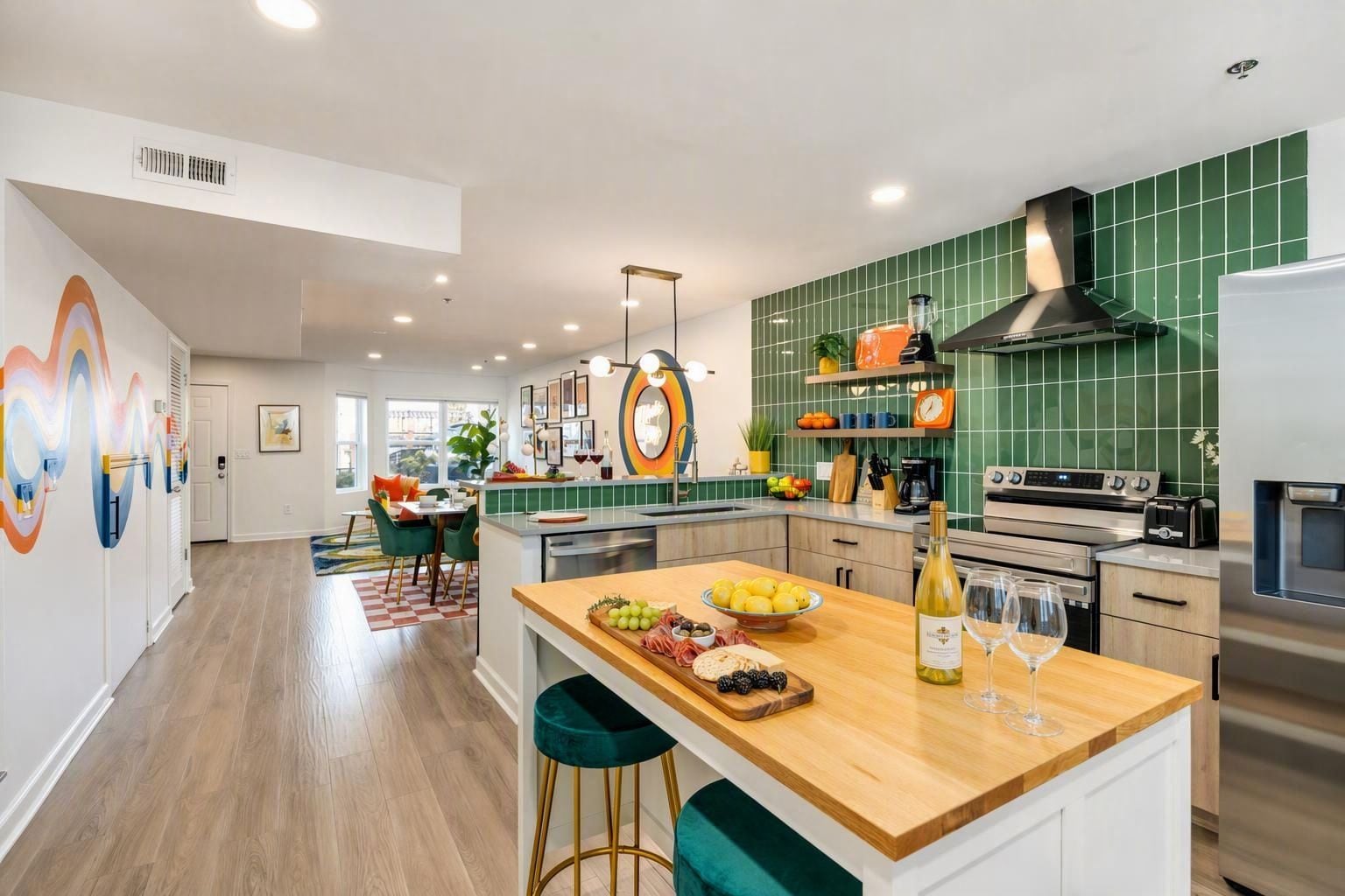 A modern kitchen with a central island, a dining area with a view, and a green-tiled backsplash.