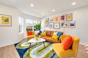 A modern living room with a sofa, armchairs, a coffee table, and a large window. - Walkable Sobro House - Gated Parking - Sleeps 8 (Nashville)