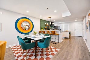 A modern kitchen with a bar area, a dining table with chairs, and a checkered rug. - Walkable Sobro House - Gated Parking - Sleeps 8 (Nashville)