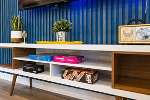 A shelf with various board games, a vintage radio, and decorative plants. - Walkable Sobro House - Gated Parking - Sleeps 8 (Nashville)