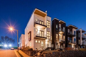 A multi-story residential building with balconies, a stone retaining wall, and a streetlight. - Gulch Rooftop Fire pit Putting Green - Sleeps 12 (Nashville)