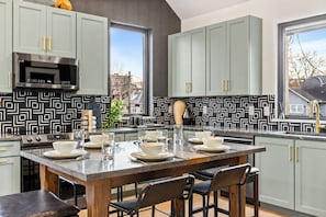 A modern kitchen with a central island, stainless steel appliances, and a patterned backsplash. - Rooftop Patio Home Near Broadway Vandy - Sleeps 12 (Nashville)