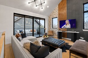 A modern living room with a sofa, a coffee table, and a TV mounted on the wall. - Rooftop Patio Home Near Broadway Vandy - Sleeps 12 (Nashville)