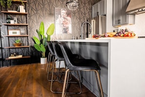 Une cuisine moderne dotée d’un îlot central, de tabourets de bar et d’un revêtement mural à motifs géométriques.