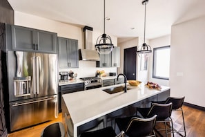 A modern kitchen with stainless steel appliances, a central island with bar stools, and pendant lighting. - Skyline Views House - 4 Ensuites - Sleeps 12 (Nashville)