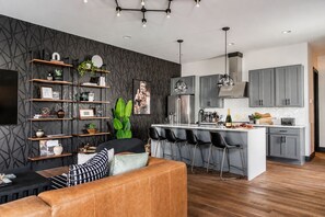 Une cuisine moderne dotée d’un îlot central, de tabourets de bar et d’un coin repas avec un canapé en cuir.
