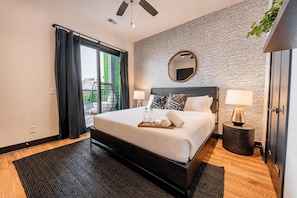 Une chambre moderne avec un grand lit, un miroir rond et une vue sur la verdure environnante.