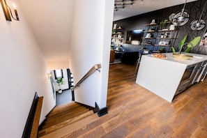 A modern kitchen with a central island, wooden flooring, and a staircase leading to another level. - Skyline Views House - 4 Ensuites - Sleeps 12 (Nashville)