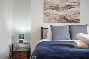 A bedroom with a bed, a nightstand, a lamp, and a painting on the wall. - Albert Street 2BR Free Wifi by Stay With Us (Chester-le-Street)