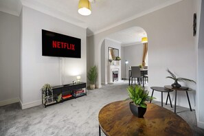 A modern living room with a flat-screen TV mounted on the wall, a coffee table, and a fireplace. - Albert Street 2BR Free Wifi by Stay With Us (Chester-le-Street)