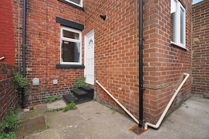A brick building with a white door, a window, and a small set of steps leading to the entrance. - Albert Street 2BR Free Wifi by Stay With Us (Chester-le-Street)