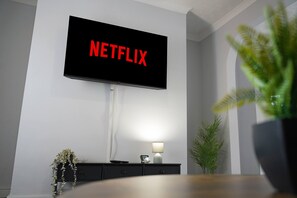 Een flatscreen-televisie bevestigd aan een muur met 'NETFLIX' in rode letters.