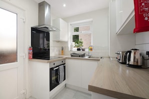 A modern kitchen with a stove, oven, and a window. - Cozy 2BR Home Sleeps 5 With Wifi by Stay With Us (Wigan)